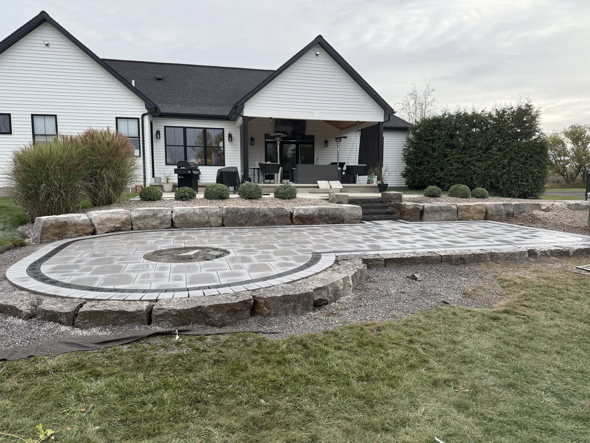 Broad backyard paver terraces with curved stone walls and steps