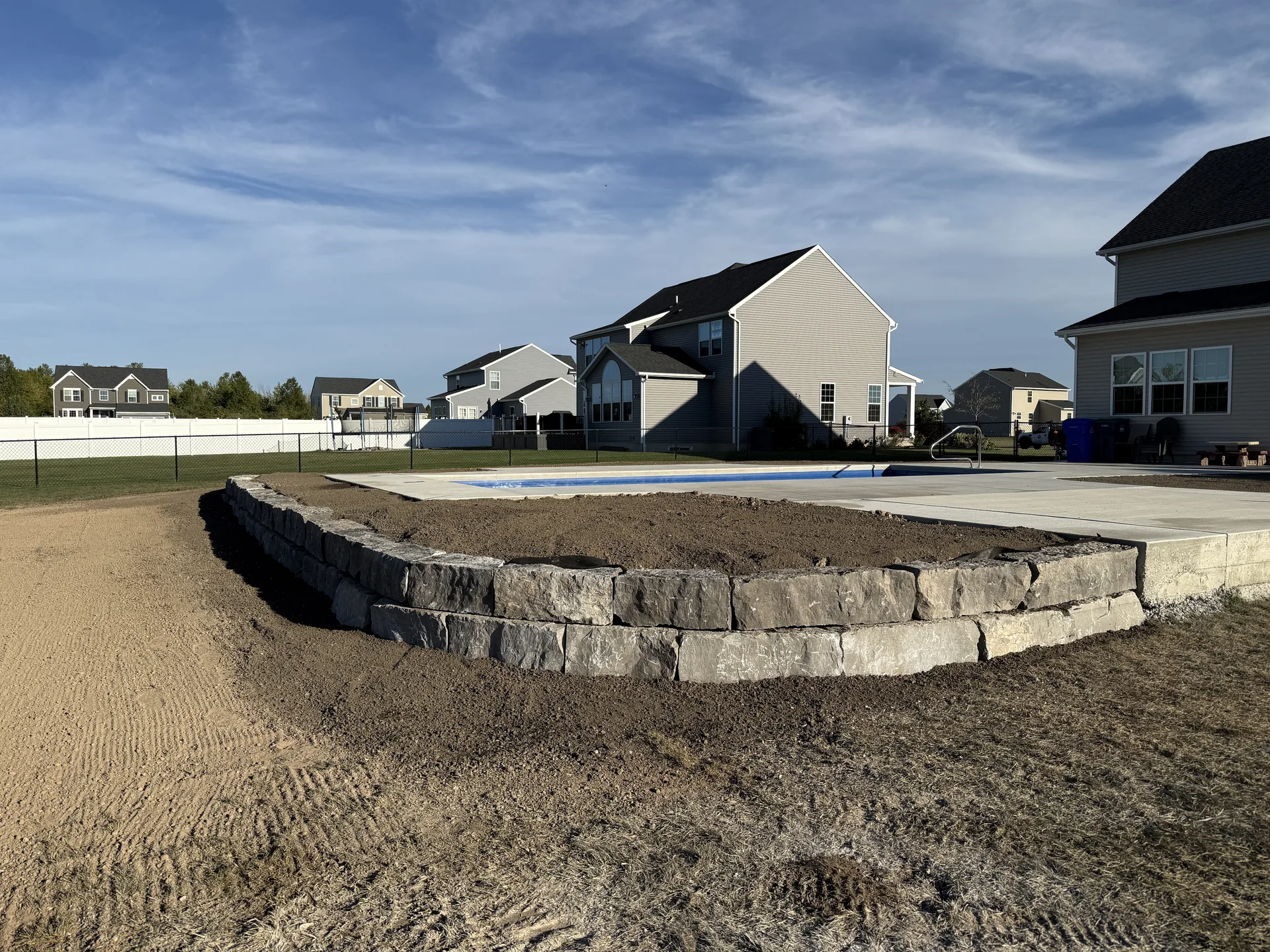 Curved block retaining wall supporting a poolside terrace